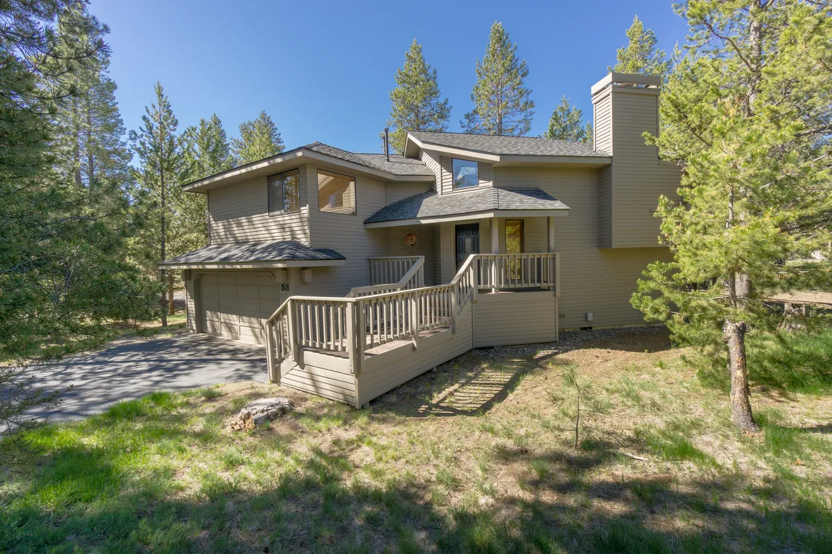 This image captures the welcoming wooden deck at the home's entrance, surrounded by towering trees. The deck is spacious, perfect for outdoor gatherings, and hints at the seamless indoor-outdoor living experience that Sunriver is known for.