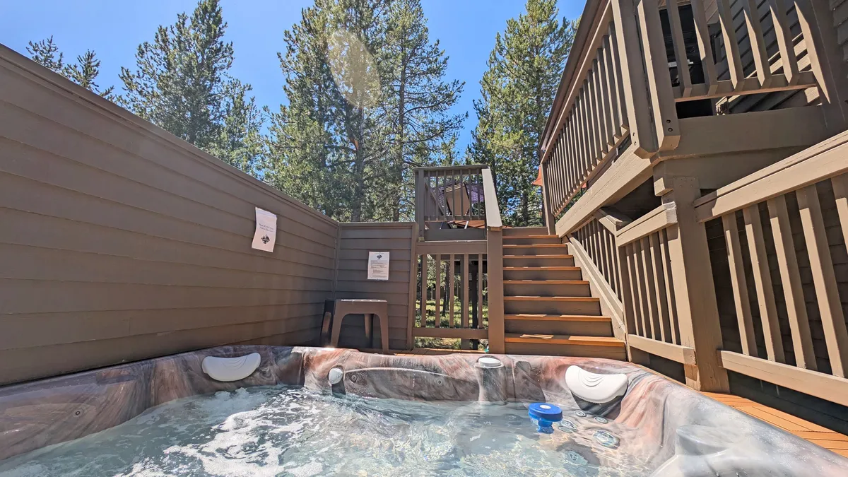 This image showcases a private hot tub nestled beside wooden stairs, surrounded by lush trees. The tranquil setting emphasizes the sense of privacy and connection with nature, perfect for evening soaks under the stars.